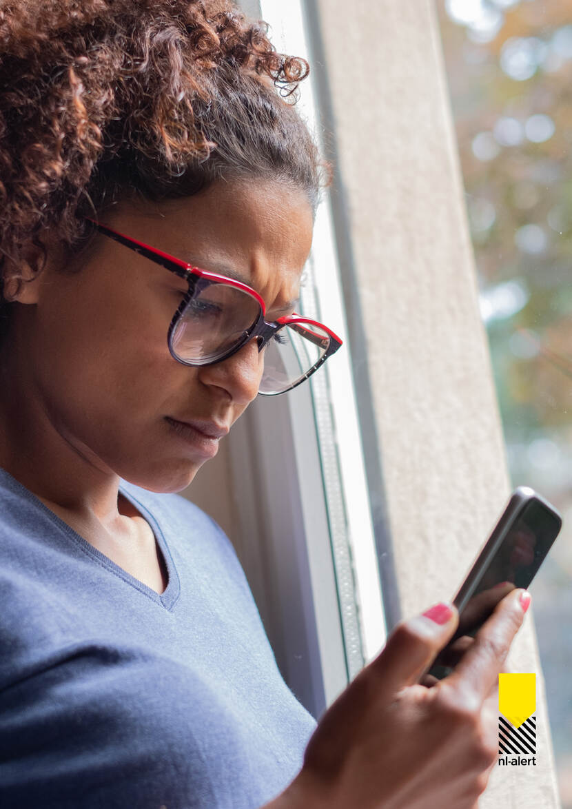 Vrouw kijkt op mobiele telefoon in haar hand.