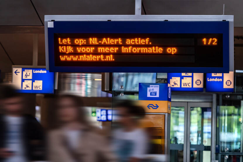 Een informatiebord van een station met de boodschap erop dat een NL-Alert actief is.